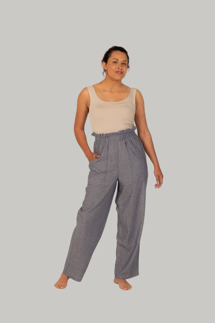 Woman wearing a beige tank top and gray checkered pants on a white background
