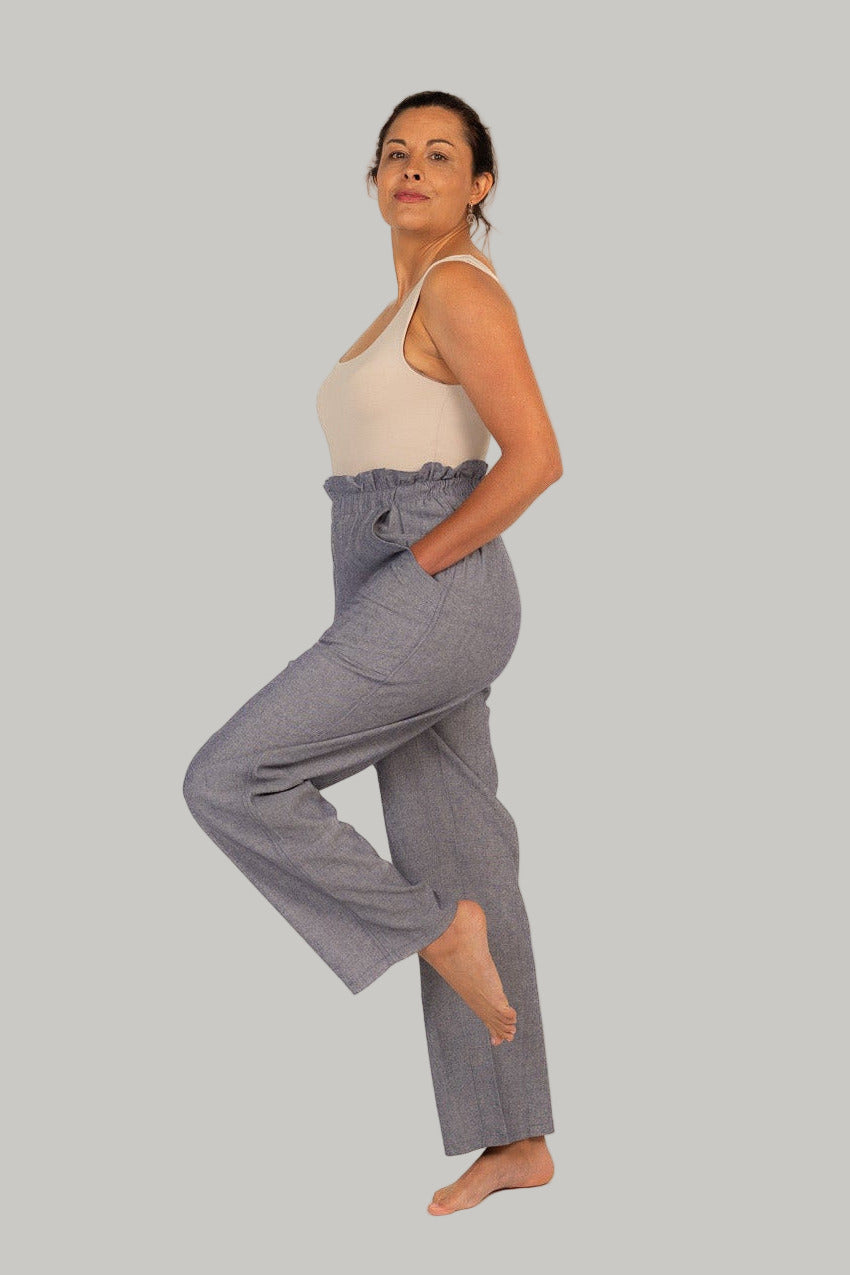 Woman wearing gray wide-leg pants and a beige top on a white background