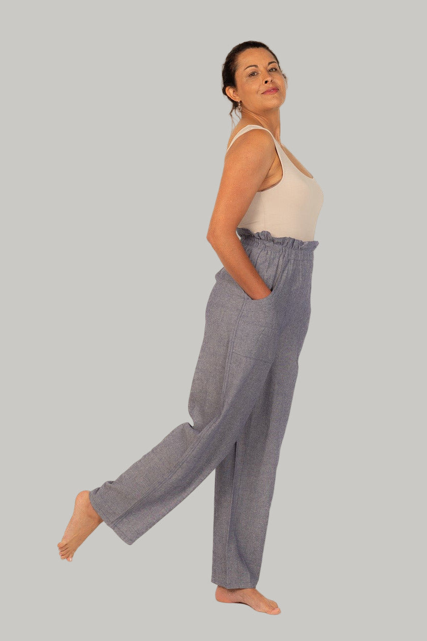 Woman wearing a beige top and gray pants on a white background