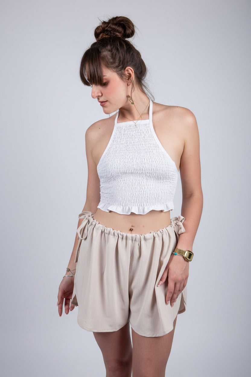 Woman wearing a white halter top and beige shorts on a white background